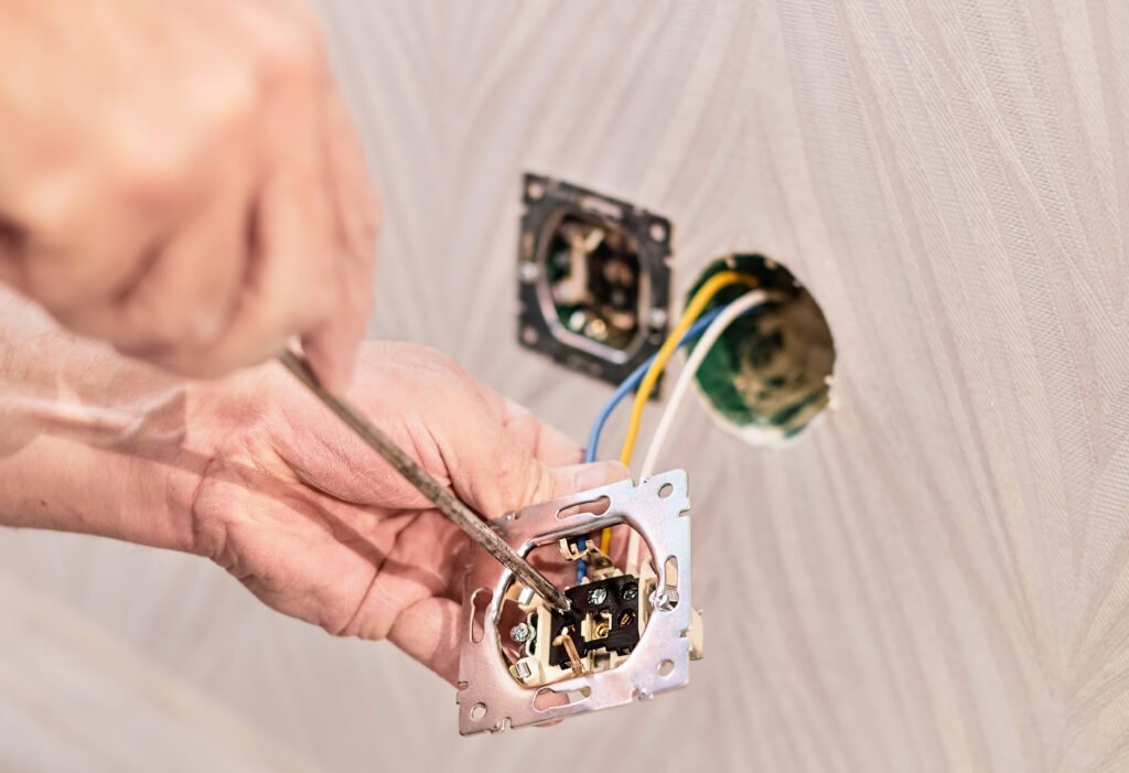 hands of an electrician installing an electrical outlet in a new house. assembly of the electrical network in the room, installation of the electrical network